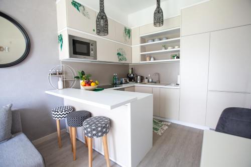 a kitchen with a white counter and stools at Apartament Panorama De Lux Family in Koszalin