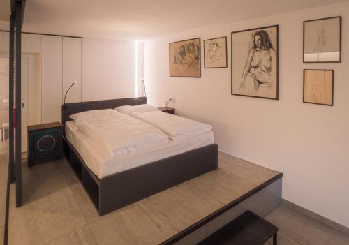 Bett in einem Zimmer mit Bildern an der Wand in der Unterkunft Sweet Piccolo Loft in centro con incantevole idromassaggio in Meran