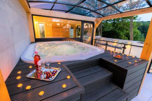 a hot tub on a deck with a table with a drink and candles at MintaMókus Vendégház in Miskolctapolca