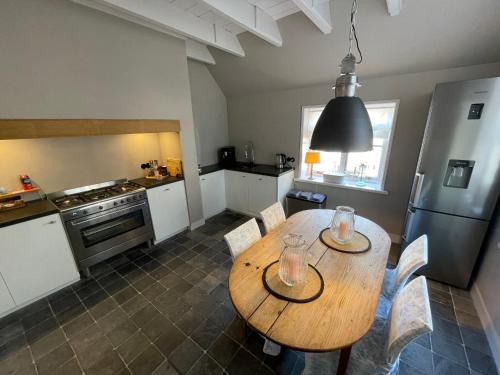 a kitchen with a wooden table with chairs and a refrigerator at Erve de Kippe. Vrij maar toch dichtbij. in Epse