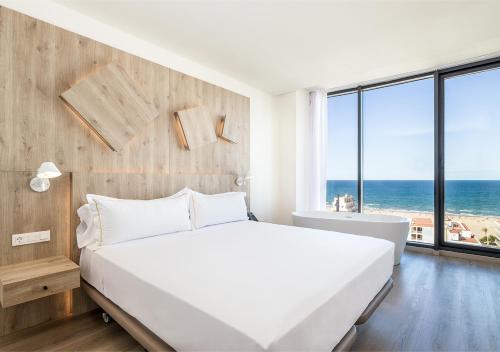 a bedroom with a white bed and a view of the ocean at Senator Gandia in Gandía
