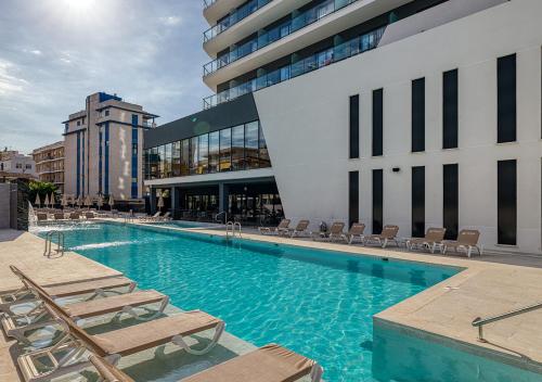 una piscina con tumbonas y un edificio en Senator Gandia en Gandía