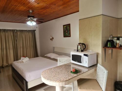 a bedroom with a bed and a table with a microwave at Tourterelle Holiday Home in Grand Anse