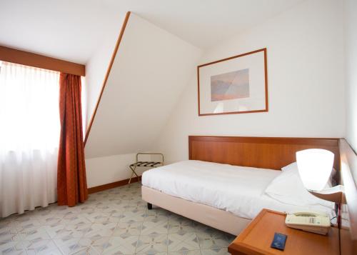 a hotel room with a bed and a desk with a phone at Hotel Europa in Rende