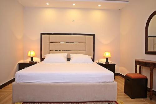 a bedroom with a large white bed with two lamps at Luxury 3 Bedrooms Apartment in Lahore