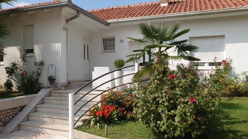 a white house with a staircase and flowers at Apartments Tulipan - with free private parking in Mostar