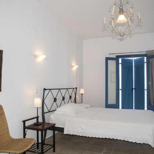 a bedroom with a bed and a chair and a chandelier at Asvestoti maisonettes Blue house in Astypalaia