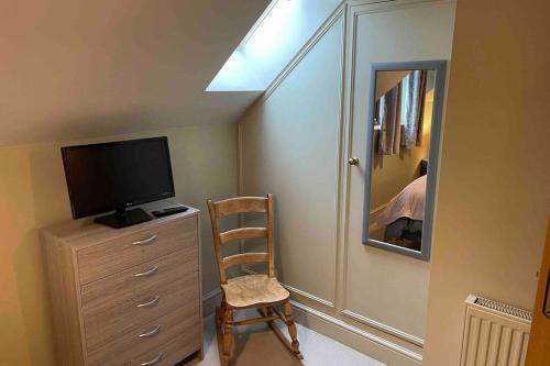 a room with a dresser with a tv and a chair at Cottage With Hot Tub in Pembrokeshire in Haverfordwest