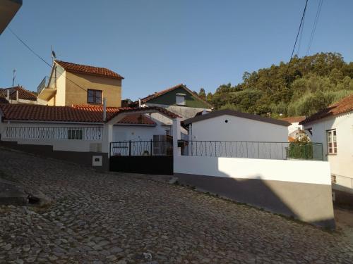 a house with a white fence and a street at Casa da Eira in Bordeiro