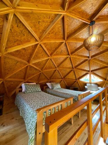 a bedroom with two beds in a wooden ceiling at Glamping y Chalet Aventura Park Villa De Leyva La Periquera in Villa de Leyva