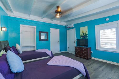 a blue bedroom with two beds and a television at Victoria House in Frederiksted