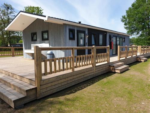 een huis met een houten veranda en een terras bij Safaritent Mini Lodge in Kesteren