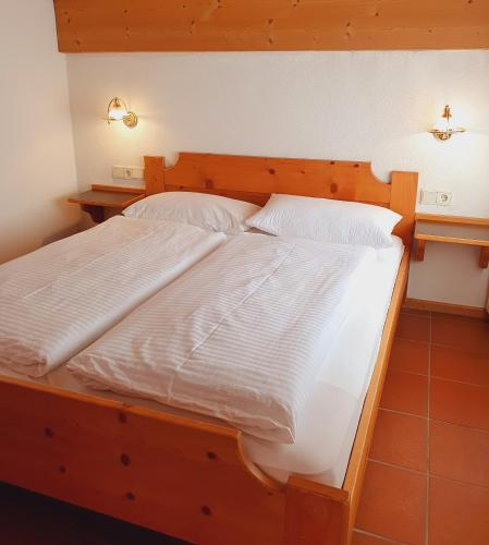 a large wooden bed with white sheets and pillows at Residence Silvester in Racines