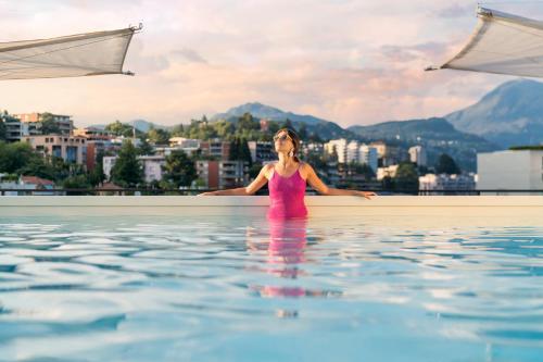 a woman standing in the water in a swimming pool at Hotel Admiral Lugano in Lugano