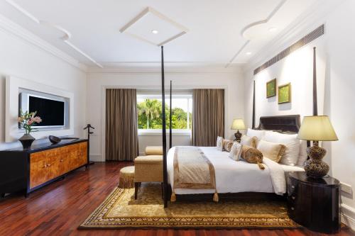 a bedroom with a large bed and a television at The Claridges New Delhi in New Delhi