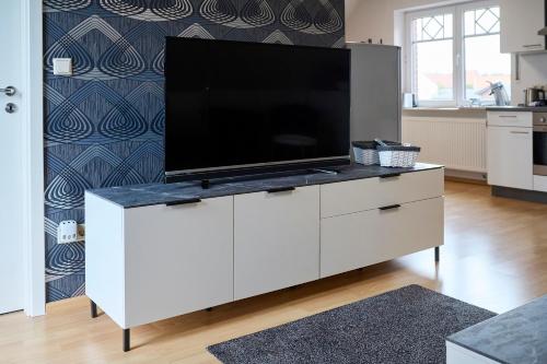 a flat screen tv on a white cabinet in a kitchen at Luxury Apartment Kampe in Stemwede
