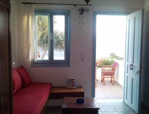 sala de estar con sofá rojo y ventana en ASVESTOTI MESONETTES BLUE LIGHT ΣΙΕΛ ΜΕΖΟΝΕΤΕs en Pera Gyalos
