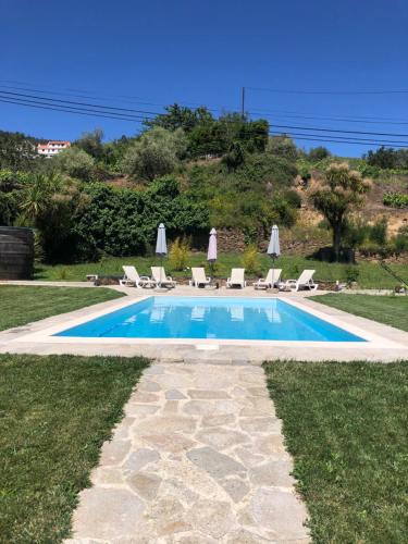 a swimming pool with chairs and umbrellas in a yard at Casa de Carrapatelo in Mesão Frio