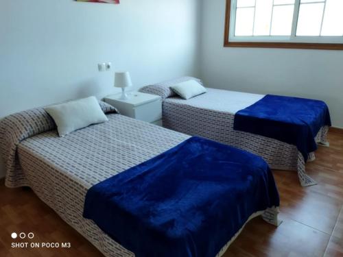 2 camas con sábanas azules en una habitación en CASA PASAXE-Bajo, en A Guarda