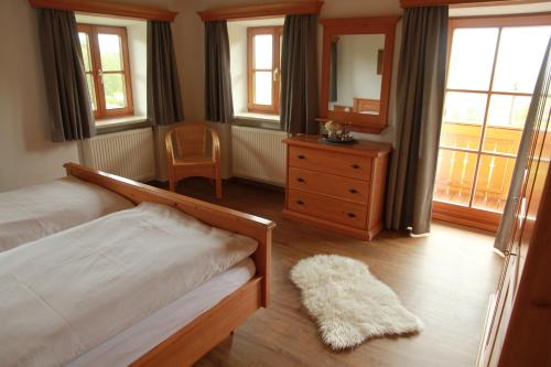 a bedroom with a bed and a dresser and windows at Ferienwohnung Fritzenwenger in Übersee