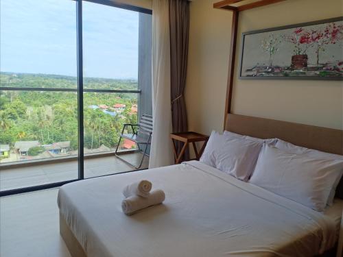 a bed with a towel on it with a large window at Timurbay Lavender Homestay in Kampung Sungai Karang