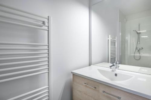 uma casa de banho branca com um lavatório e um chuveiro em Bel appartement pour 6 personnes avec balcon en bord de mer em Pléneuf-Val-André
