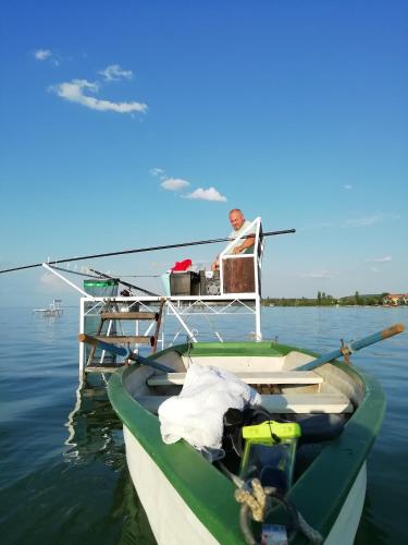 a man sitting in a chair on a boat in the water at SUNFISH Apartman in Balatonszárszó