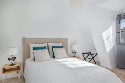 une chambre avec un grand lit blanc avec des oreillers bleus dans l'établissement À 50m de la plage, bel appartement sous les toits, à Pléneuf-Val-André