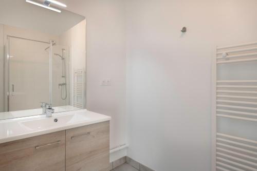 une salle de bain blanche avec un lavabo et une douche dans l'établissement À 50m de la plage, bel appartement sous les toits, à Pléneuf-Val-André