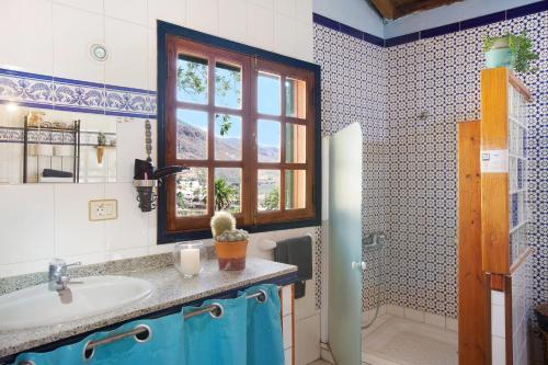 Un baño con lavabo, inodoro y ventana. en Casa Los Pinos, en Agüimes
