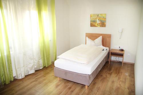 Schlafzimmer mit einem Bett, einem Tisch und einem Fenster in der Unterkunft Gaststätte Wicke in Baunatal