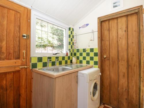 eine Küche mit einer Spüle und einer Waschmaschine in der Unterkunft Mackerel Cottage in Budleigh Salterton