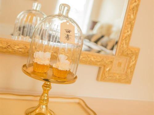 a glass dish with cupcakes in it on a table with a mirror at Queen Bee & B in Merthyr Tydfil