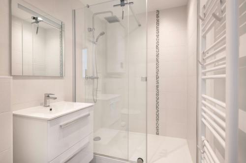 une salle de bain blanche avec un lavabo et une douche dans l'établissement Appartement pour 4 avec vue sur la marina, à Pornichet