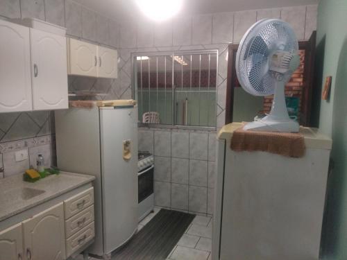 a kitchen with a white fan on top of a refrigerator at Casa 50 mts da praia Caravelas PR com ventiladores in Matinhos