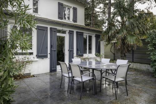 un patio avec une table et des chaises devant une maison dans l'établissement Villa « Les Libellules » pour 8 personnes, à La Baule