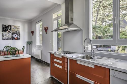 een keuken met een wastafel en 2 ramen bij Villa Les Libellules pour 8 à 9 personnes in La Baule