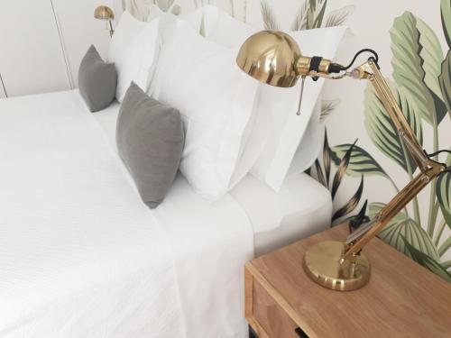 a bed with white pillows and a desk with a lamp at Vera Cruz Suite Apartment in Aveiro