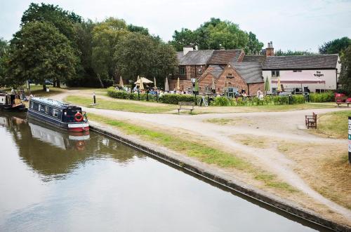 a boat traveling down a river next to a village at The Cottage in Willington