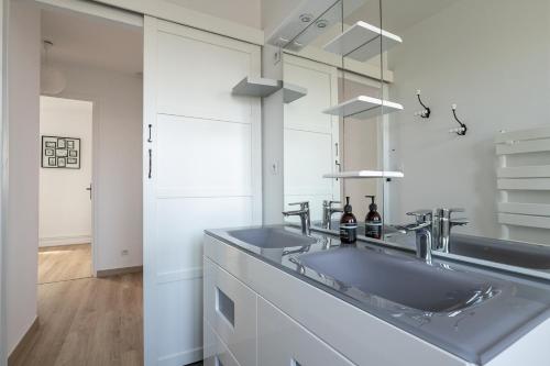 une salle de bain avec deux lavabos et un grand miroir dans l'établissement Des vacances en bord de mer pour 10 personnes, à Château-dʼOlonne