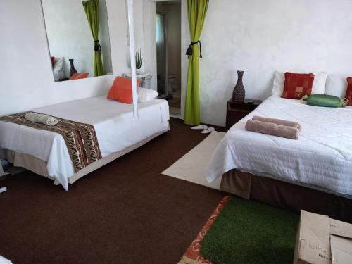 a bedroom with two beds and a green rug at Rocks And Aloes Guest Lodge in KwaGamalakhe