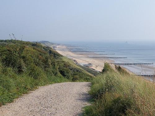 a dirt road leading to a beach with a pier at Room by the sea in Zoutelande