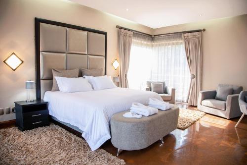a bedroom with a large white bed and a chair at Schimper View Boutique Guest House in Louis Trichardt