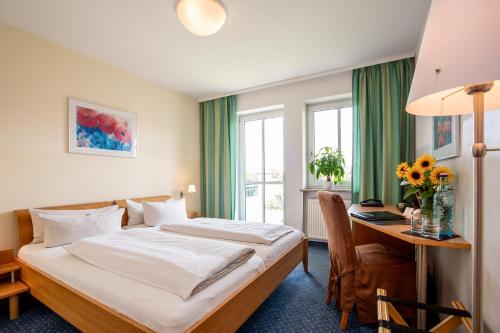 a hotel room with a bed and a desk at Arcus Hotel München Messe in Feldkirchen