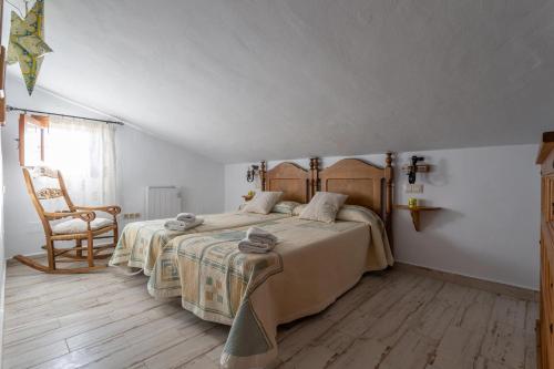 a bedroom with two beds and a chair at Fuente luz cottage in Frigiliana