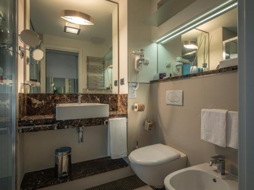 a bathroom with a toilet and a sink and a mirror at Parc Hotel Gritti in Bardolino