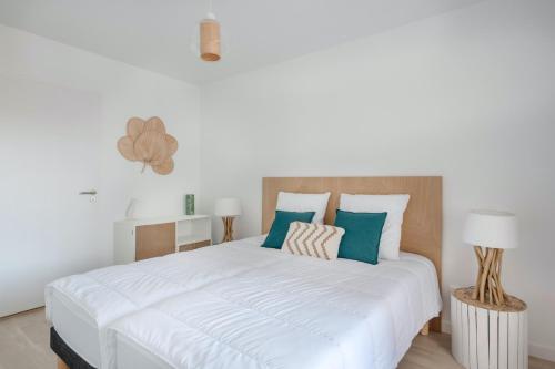 - une chambre avec un grand lit blanc et des oreillers verts dans l'établissement La plage de Val Andre au pied de l appartement, à Pléneuf-Val-André