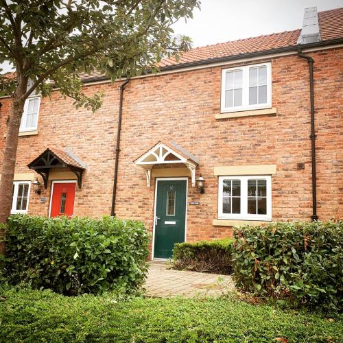 a brick house with a green door and white windows at The Bay, Filey, Moonshine Cottage in Filey