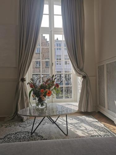a vase of flowers on a glass table in front of a window at Molenmeers Boutique Guesthouses in Bruges