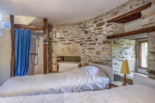 a bedroom with two beds and a stone wall at Nuit insolite sur la presqu'île de Rhuys in Sarzeau